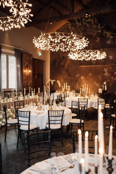 Elegant reception space featuring candlelit tables, black Chiavari chairs, and stunning floral chandeliers for a romantic ambiance.