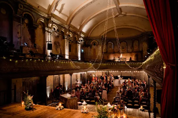 Elegant vintage venue featuring exposed brick walls, a grand chandelier, and warm candlelight, perfect for a romantic ceremony.