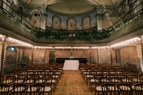 A charming ceremony space featuring vintage wooden chairs, rustic walls, and soft lighting, creating an intimate atmosphere for weddings.