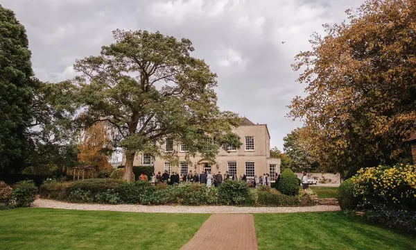 Charming outdoor ceremony space featuring a lush green lawn, elegant mansion backdrop, and mature trees for a romantic setting.