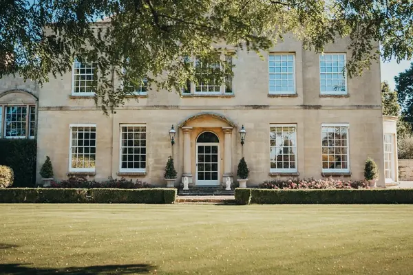 Elegant historic manor with large windows, manicured lawn, and charming entrance, perfect for romantic wedding ceremonies and celebrations.
