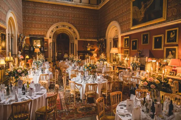 Elegant reception hall adorned with floral centerpieces, classic artwork, and warmly lit tables, creating a romantic atmosphere for weddings.