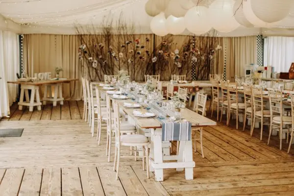 Rustic reception space featuring long wooden tables, elegant decor, and soft lighting, perfect for an intimate wedding celebration.
