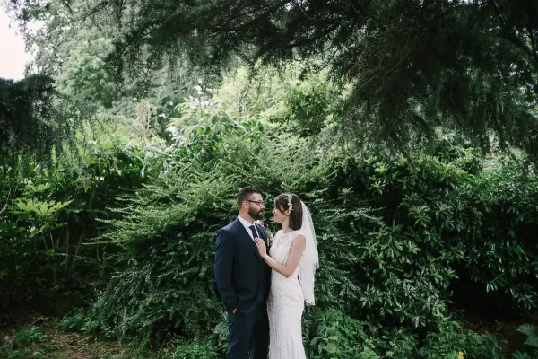 Intimate couple portrait surrounded by lush greenery, creating a romantic backdrop for outdoor wedding ceremonies.