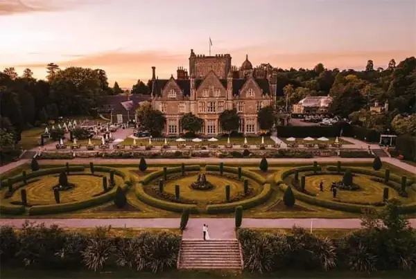 Stunning aerial view of a grand mansion surrounded by elegantly manicured gardens and ornamental hedges, perfect for a romantic outdoor ceremony.