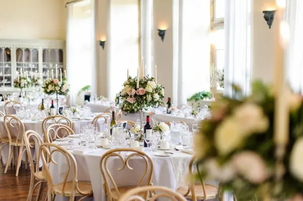 Elegant dining space featuring round tables set with fine china, floral centerpieces, and soft candlelight, perfect for a romantic reception.