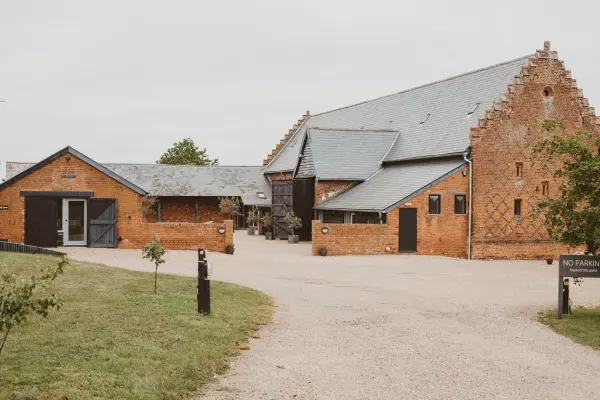 Charming rustic barn wedding venue features a unique brick facade and inviting entrance, surrounded by landscaped greenery.