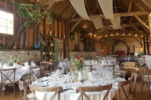 Charming rustic barn venue with elegant round tables, twinkling lights, and lush greenery, perfect for an intimate wedding celebration.