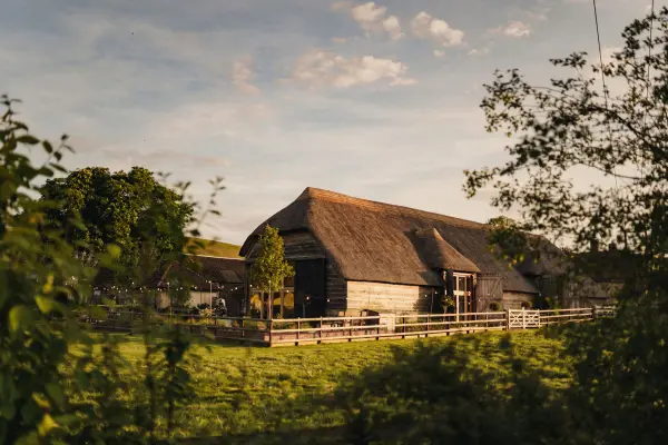 Charming rustic barn set against a serene landscape, surrounded by lush greenery and soft evening light, perfect for intimate weddings.