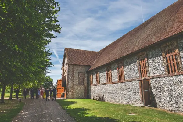 Charming rustic barn venue with stone walls, surrounded by greenery and a pathway, perfect for outdoor wedding celebrations.