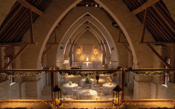 Rustic barn venue featuring elegant arched ceilings, softly lit reception area, and beautifully set round tables for a romantic celebration.