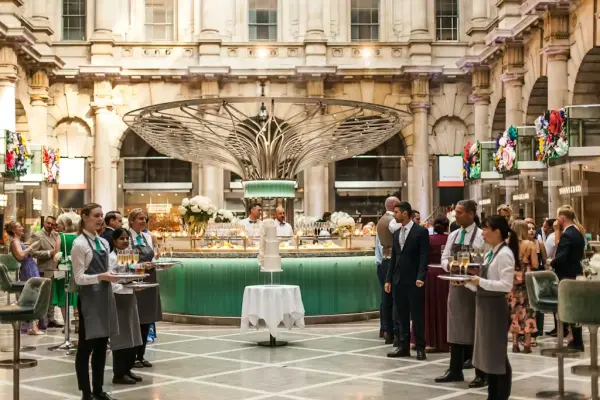 Elegant indoor wedding venue with a stunning central bar, attendants serving drinks, and guests mingling in a beautifully designed space.