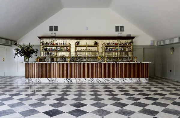 Elegant bar area with a marble-tiled floor, stylish wooden accents, and a backdrop of shelves filled with fine spirits. Perfect for cocktail hours.