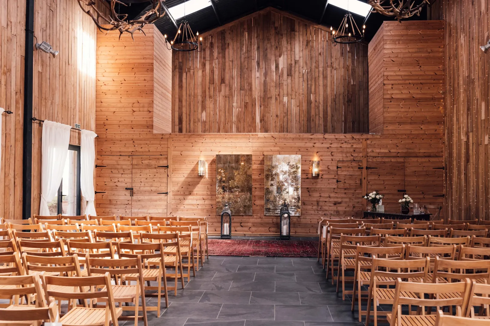 Warm rustic barn venue featuring wooden walls, elegant seating, and a charming altar, perfect for intimate wedding ceremonies.