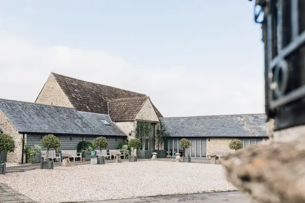Charming stone barn venue featuring a spacious outdoor courtyard, landscaped with potted trees and rustic seating. Perfect for intimate gatherings.