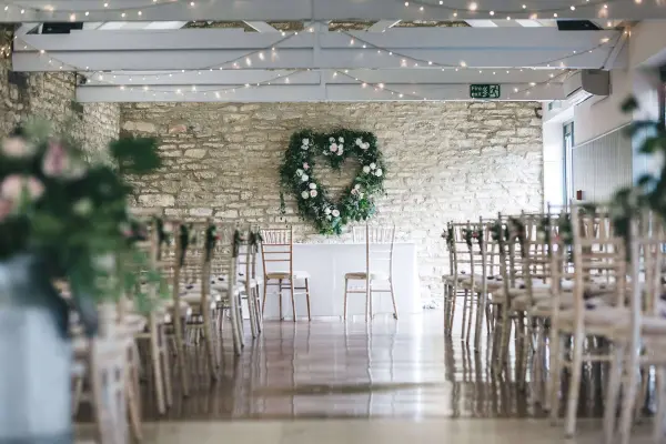 Rustic venue with exposed stone walls, twinkling fairy lights, and a heart-shaped floral arrangement creating a romantic ambiance for weddings.