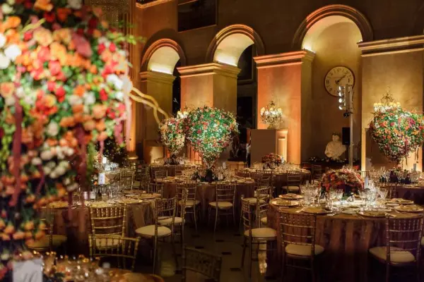 Elegant banquet hall with grand arches, lavish floral arrangements, tall centerpieces, and sparkling table settings for a romantic wedding.