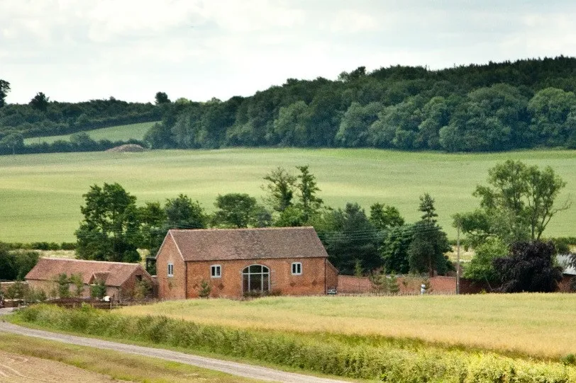 Charming rustic barn surrounded by lush greenery and rolling hills, ideal for scenic outdoor wedding ceremonies. Perfect countryside setting.