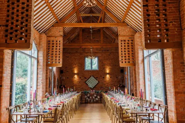 Rustic charm of a warm, exposed brick dining area featuring long wooden tables, elegant centerpieces, and large windows for natural light.