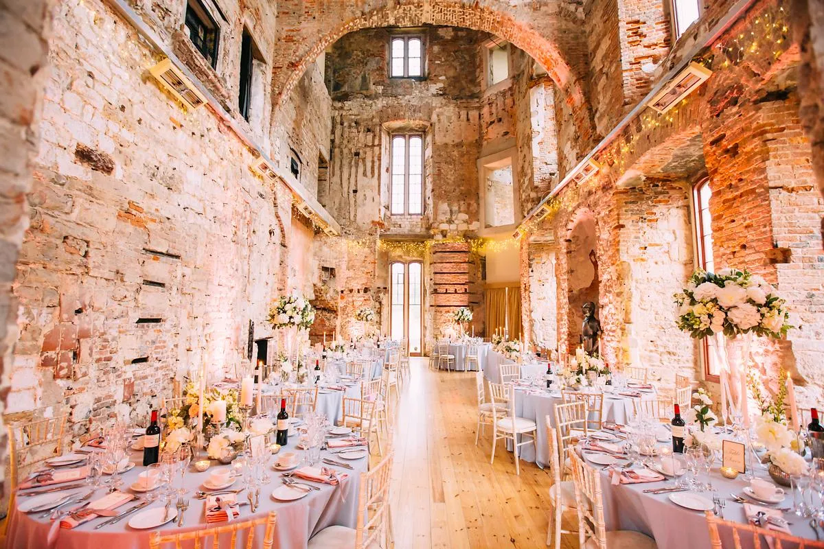 Rustic venue featuring exposed brick walls, elegant tables set with floral arrangements, and warm, ambient lighting for a charming wedding reception.