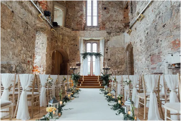 Charming rustic chapel featuring stone walls, wooden accents, and an elegant aisle adorned with greenery and lanterns for a romantic ceremony.