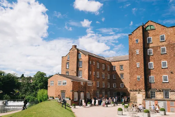 Charming brick wedding venue featuring lush green lawns, outdoor gathering spaces, and scenic views near a tranquil river.
