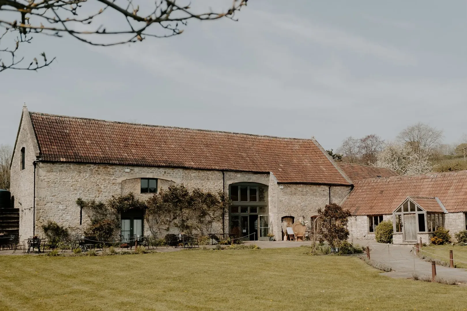 Charming rustic barn venue with stone exterior, lush green lawn, and beautiful garden for inviting outdoor ceremonies and celebrations.
