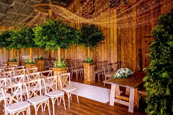 Rustic indoor ceremony space featuring elegant wooden decor, lush greenery, and soft lighting, perfect for intimate weddings.