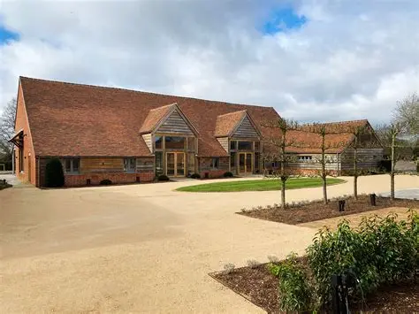 Charming rustic barn with a gravel drive, surrounded by manicured landscaping and trees, ideal for picturesque outdoor weddings.