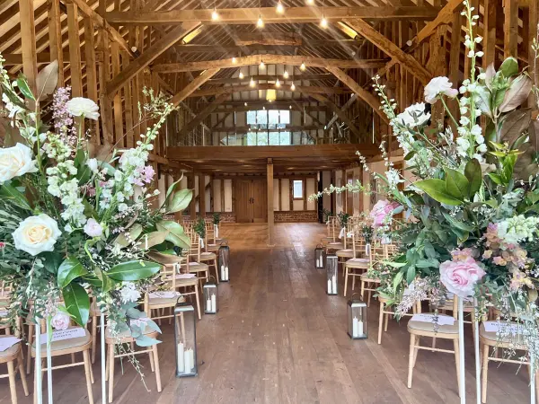 Rustic barn venue featuring wooden beams, floral arrangements, and elegant seating, perfect for an intimate wedding ceremony.