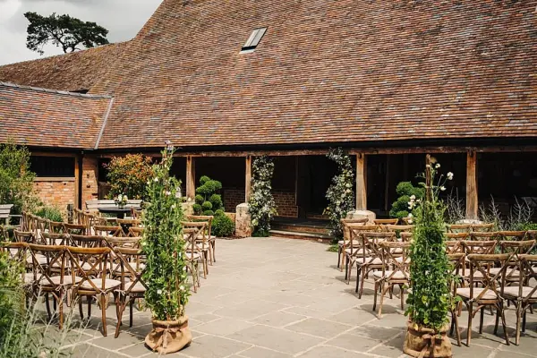 Charming outdoor ceremony space featuring rustic wooden chairs, lush greenery, and elegant floral accents, perfect for intimate weddings.