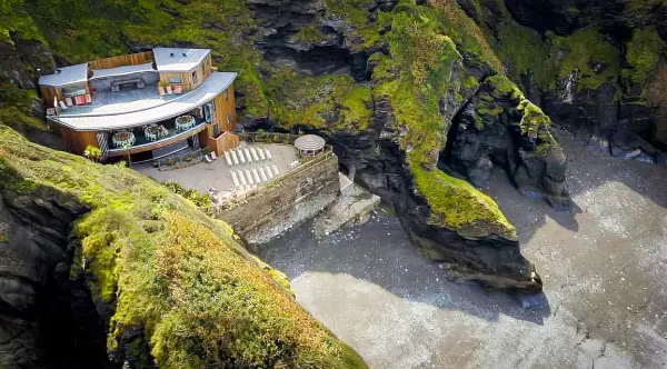 Secluded wedding venue nestled in cliffs, featuring a modern space with a scenic outdoor ceremony area overlooking the coastline.