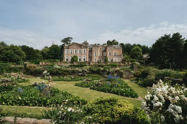 Stunning historical mansion amid lush gardens, featuring colorful flower beds and manicured lawns for picturesque outdoor ceremonies.