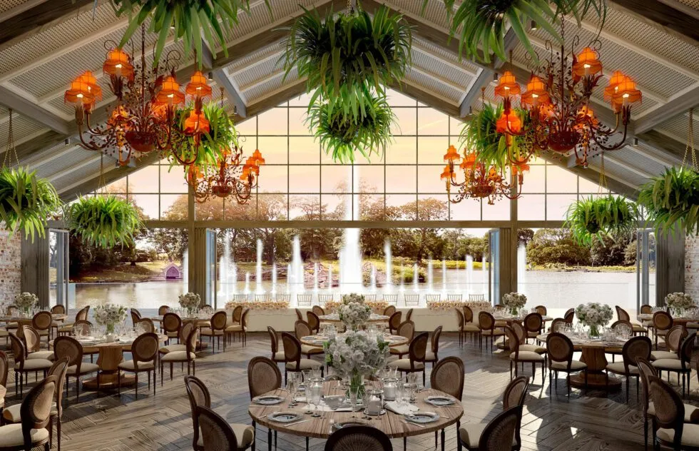 Elegant reception space with chandelier lighting, lush greenery, and large windows showcasing a scenic waterfront view. Perfect for a romantic wedding.