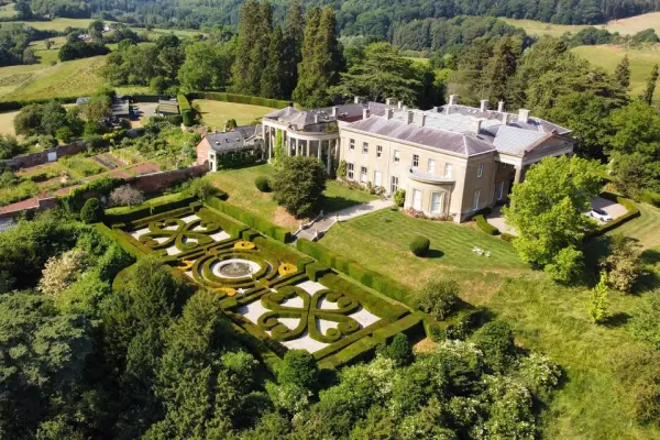Aerial view of a grand estate featuring manicured gardens, elegant architecture, and scenic countryside, perfect for outdoor ceremonies.