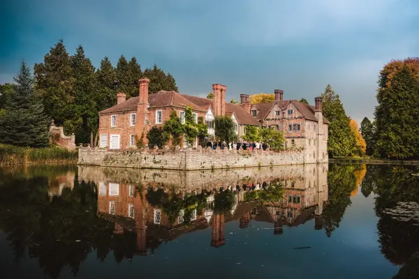A charming historic estate reflecting in the serene water, surrounded by lush greenery, ideal for a romantic outdoor wedding.