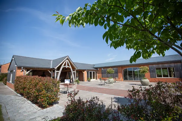 Charming rustic venue with a spacious outdoor patio, lush landscaping, and striking architectural details, perfect for wedding celebrations.