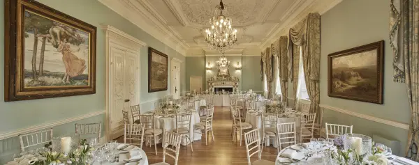Elegant ballroom featuring soft blue walls, ornate chandeliers, and beautifully set tables adorned with floral centerpieces.