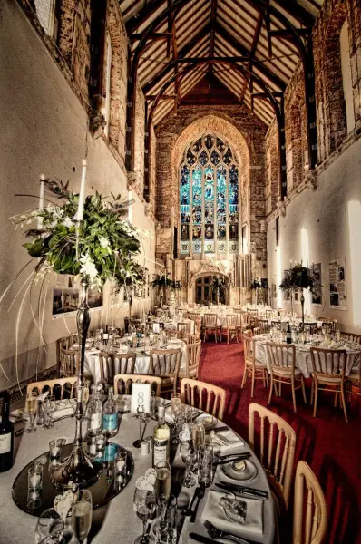 Stunning interior with vaulted ceilings, elegant tables, and a beautiful stained glass window, perfect for a romantic wedding reception.