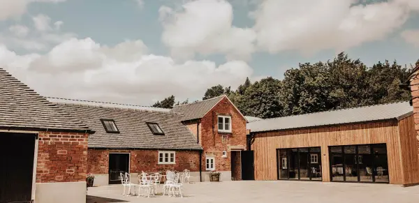 Charming rustic barn venue with elegant wooden accents, outdoor seating area, and lush greenery, perfect for intimate weddings.