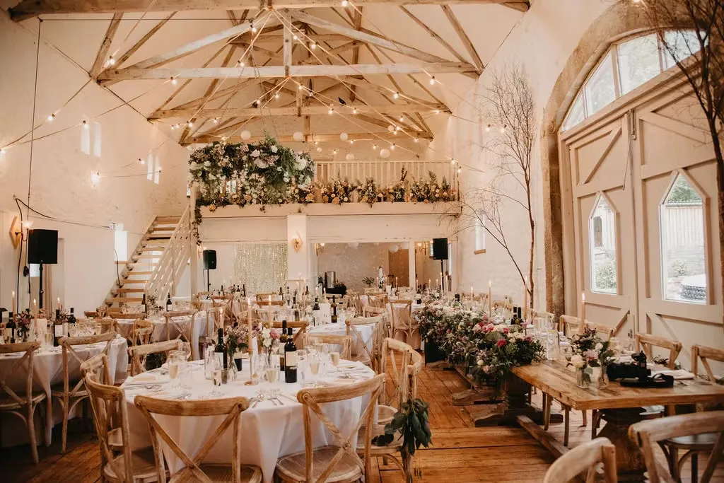 Elegant barn venue featuring rustic wooden beams, stylish table settings, and lush floral arrangements for an intimate wedding reception.