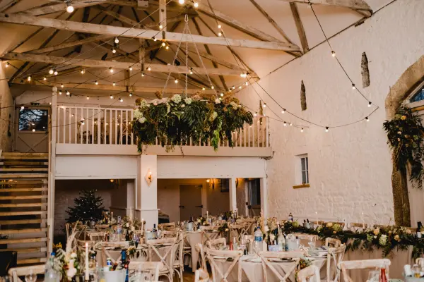 Rustic barn wedding venue featuring elegant tables, string lights, and lush greenery, creating a warm, inviting atmosphere for celebrations.