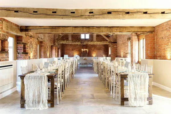 Warm rustic venue featuring long wooden tables, elegant chiavari chairs, and exposed brick walls, ideal for intimate wedding receptions.