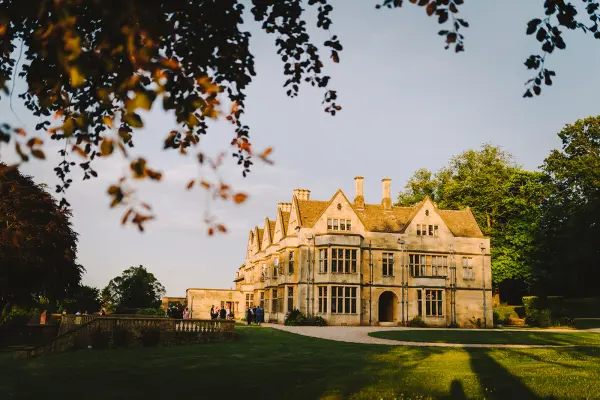 Stunning historic mansion with elegant stone facade, surrounded by lush greenery and landscaped gardens, perfect for outdoor ceremonies.