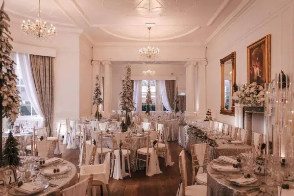 Elegant banquet room featuring sparkling chandeliers, draped curtains, and tastefully decorated tables set for a wedding reception.